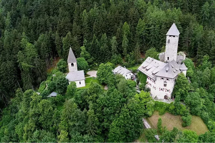 Schloss Neuhaus mit Turm und Kapelle, umgeben von grünem Wald